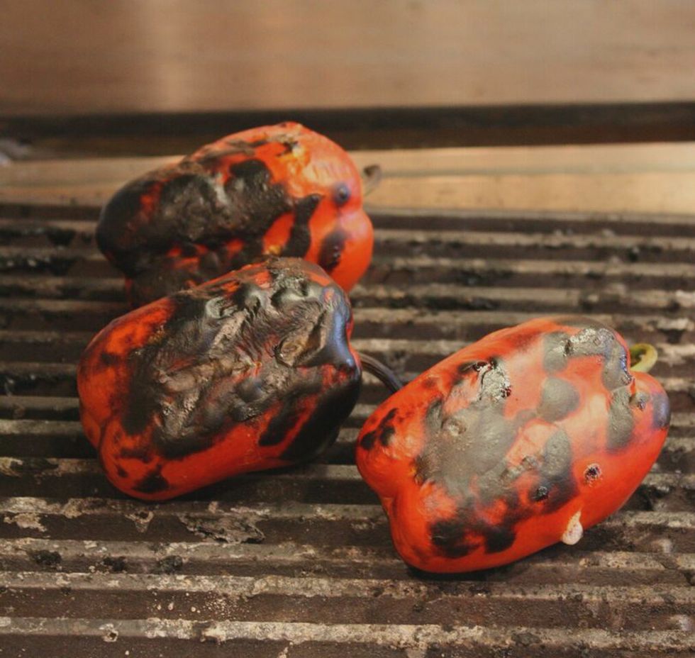 On a char grill or an open flame, blister the peppers until the skin has become bubbled and blackened.