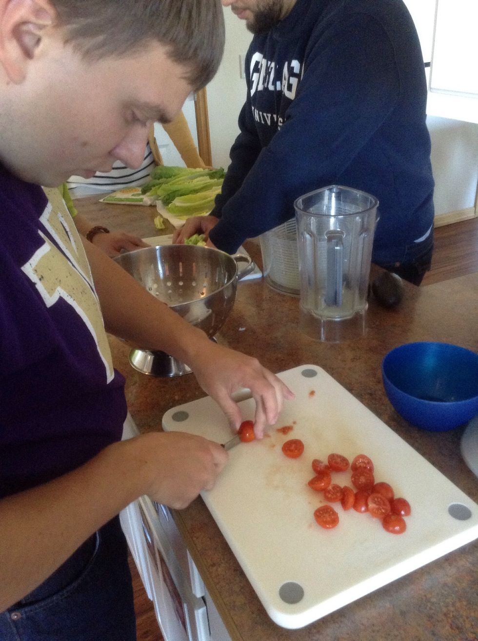 On a cutting board carefully using knife cut the tomatoes in half