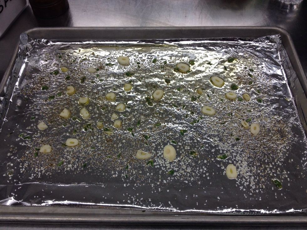 On a foil lined half sheet tray, coat with olive oil, sliced garlic, thyme leaves, salt, and pepper.