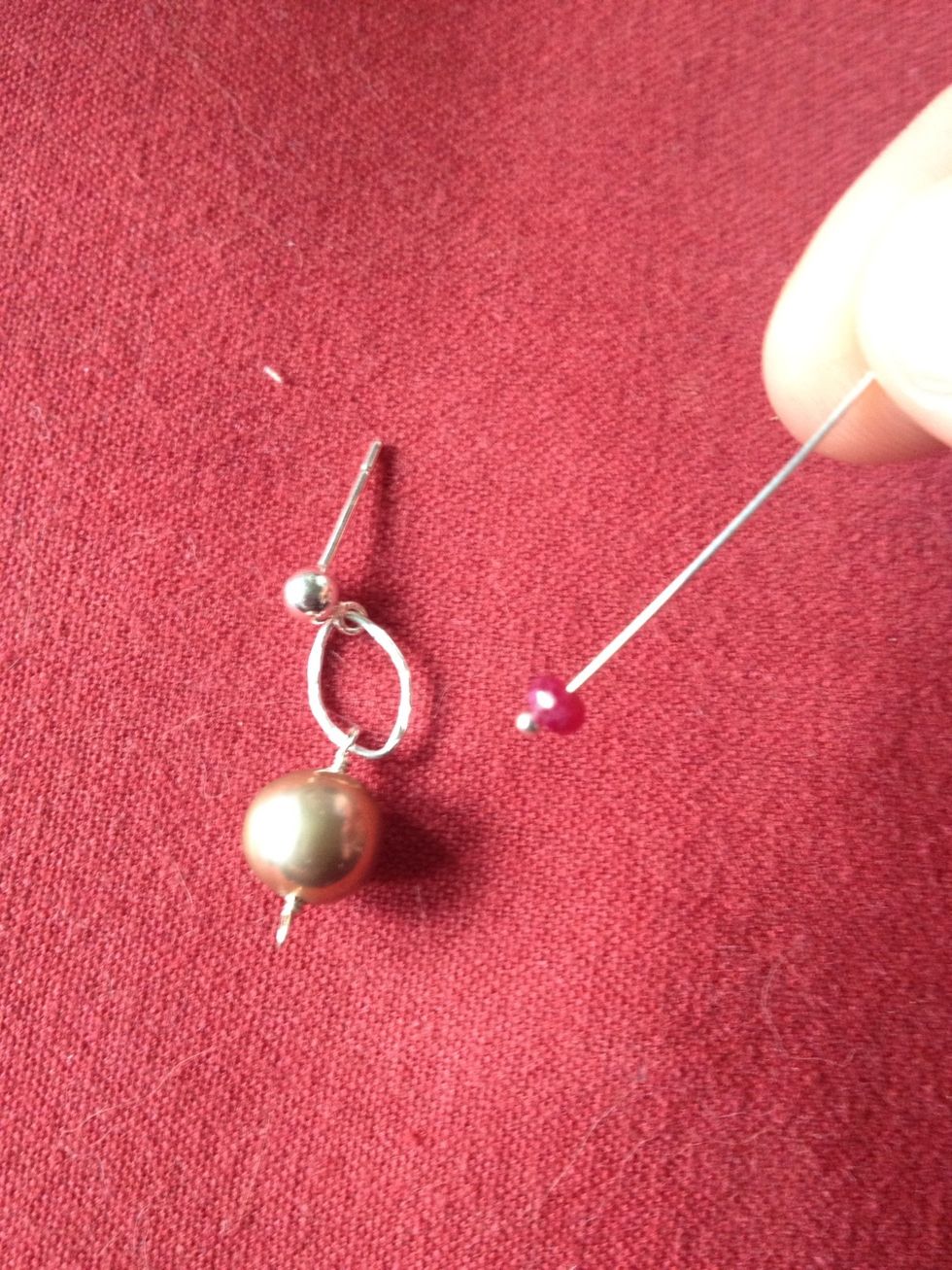 On a head pin, add the bead you plan to drop from the bottom. Here I have used an unpolished ruby.