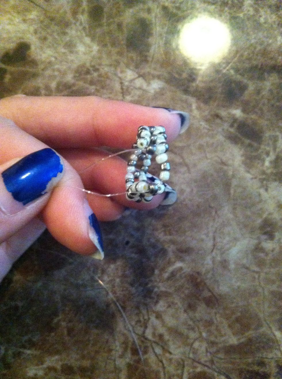 On one end string a white, silver, and white bead and cross the cord through the opposite side's silver bead to create a ring shape