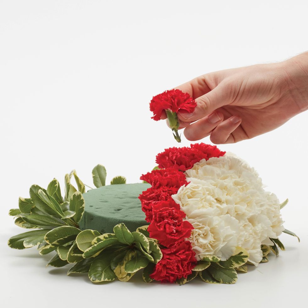 On one half, insert red mini carnations in a curve from one side to the other to create the "stitching",
