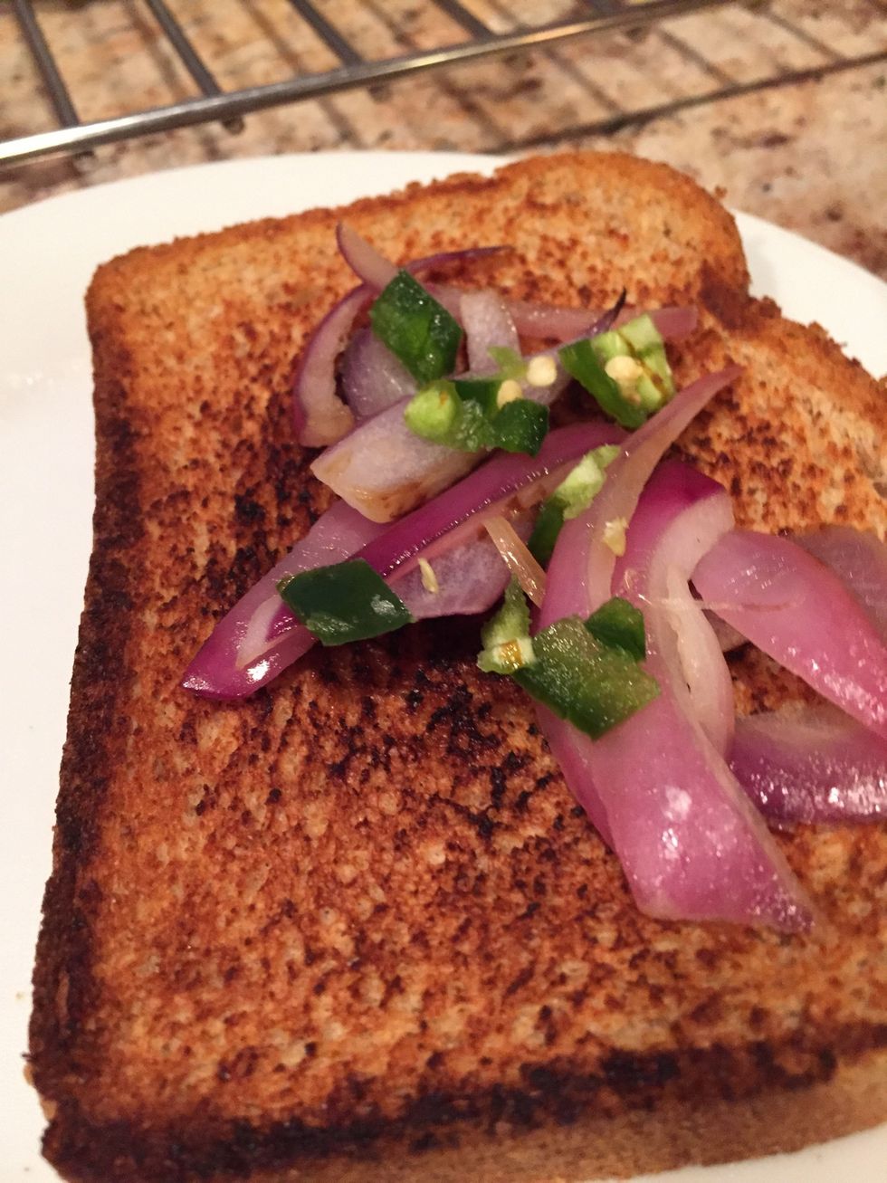 On the brown side of the toasted slice, spread the onions and jalape\u00f1o peppers