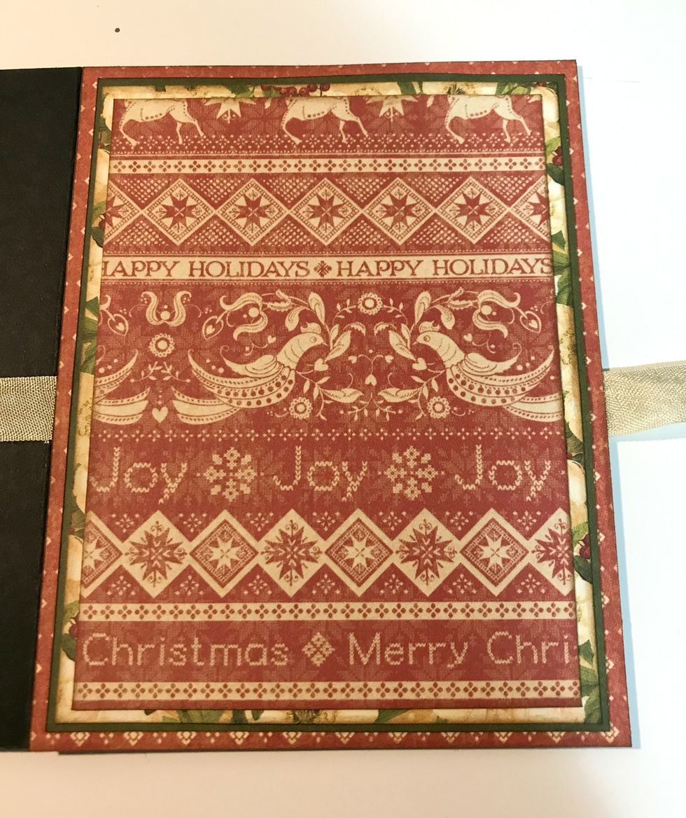 On the front left cardbase panel, adhere red diamond paper to cardbase. Adhere red paper to flower paper. Adhere flower paper to green paper. Adhere green paper to diamond paper.