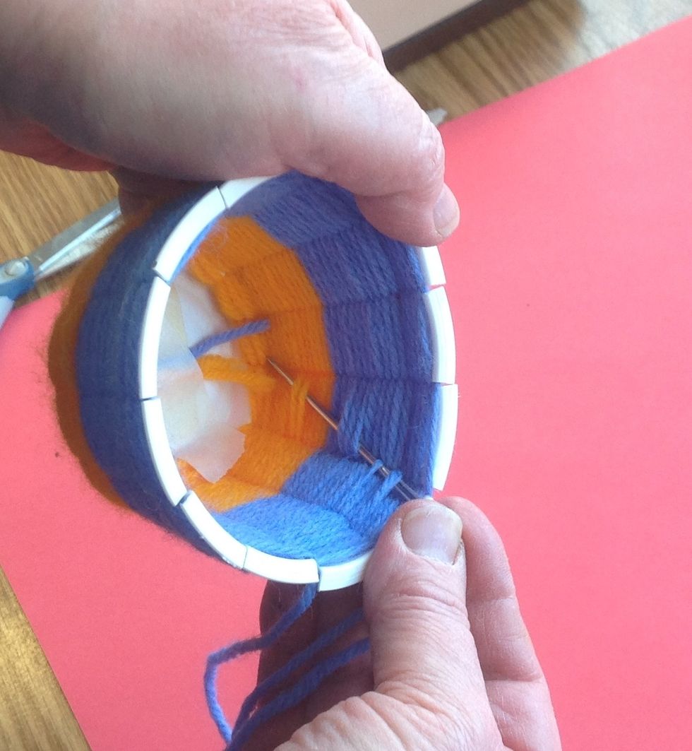 On the inside, moving from the top down towards the base, weave the needle in and out between the weft (rows). When you reach the base cut off the yarn leaving around half an inch hanging out.