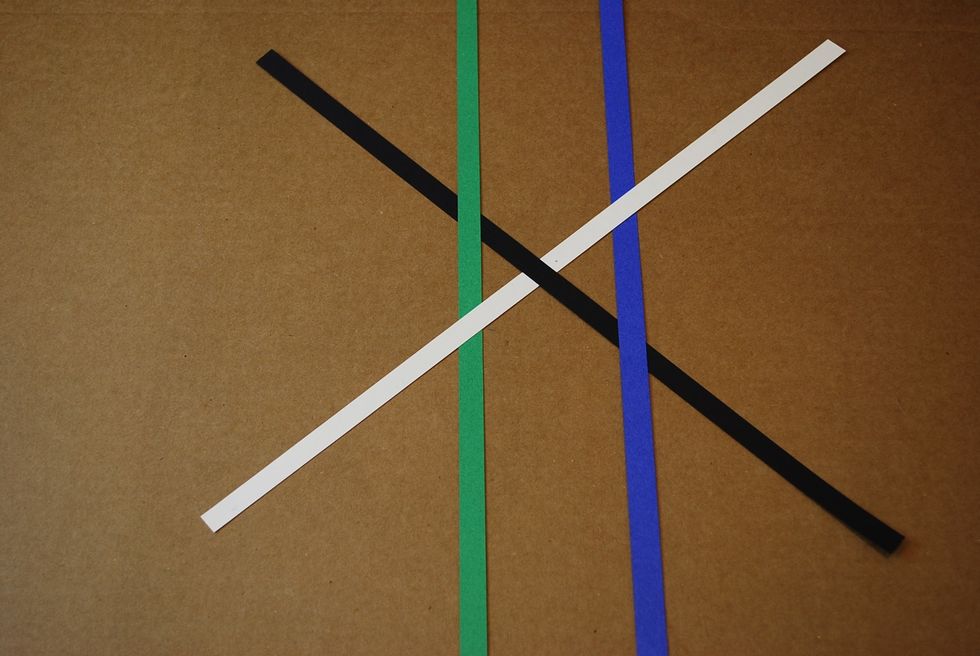 On the left side of the X, slide the green strip over the black and under the white strip.
