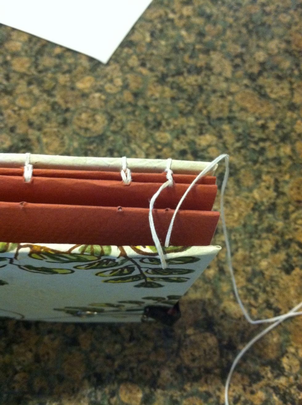 On the outside put the thread through the first signature in the cardboard outside to the inside