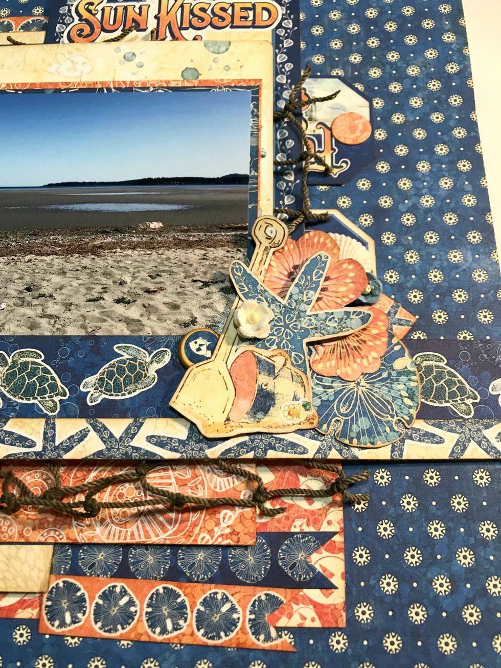 On the right hand side of the photo adhere the shell, both chipboard elements, 1 pink flower bunch, 1 sand dollar, 1 starfish, bucket with shovel, 1 white flower & 1 blue flower.