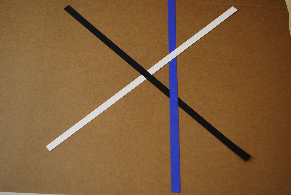 On the right side of the X, slide the blue strip under the white and over the black strip.