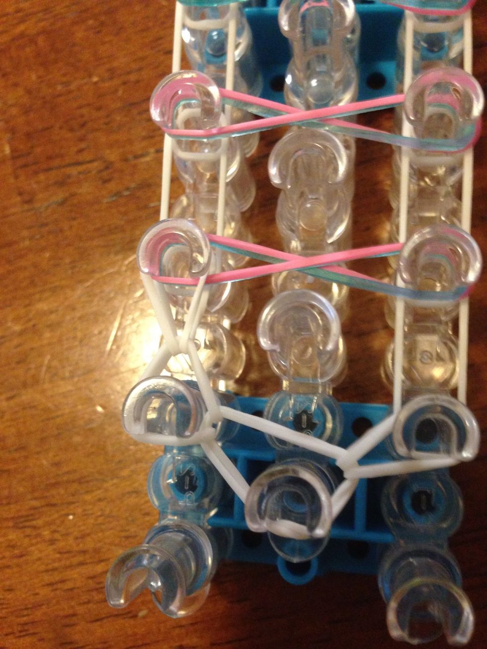 On the second left pin, take the only band on it and stretch it up a pin.