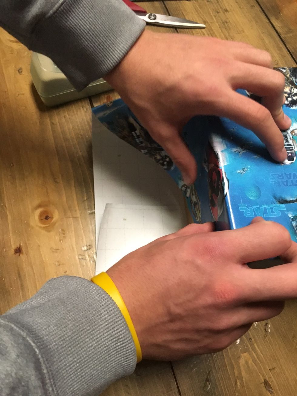 On the sides of the gift, fold the wrapping paper down. Tape it to secure it in place.