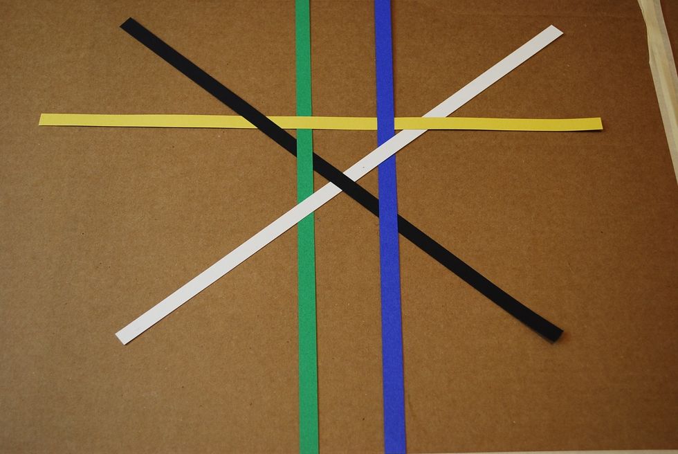 On the top side of the X, slide a yellow strip under the black, over the green, under the blue, and over the white.