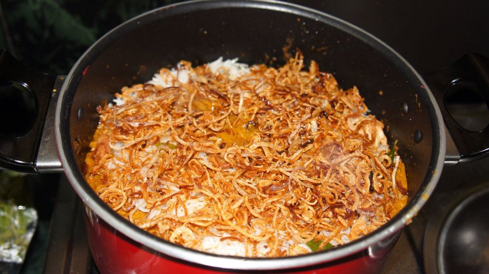 On top of chicken put a layer of half boiled basmati rice then fried onions...