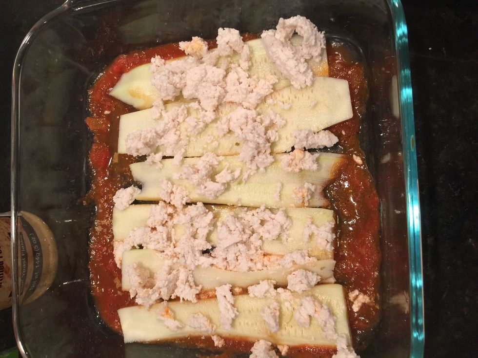 On top of the pasta sauce add your zucchini spears then layer on top of them vegan ricotta. Sprinkle onion garlic lack pepper powder mix.