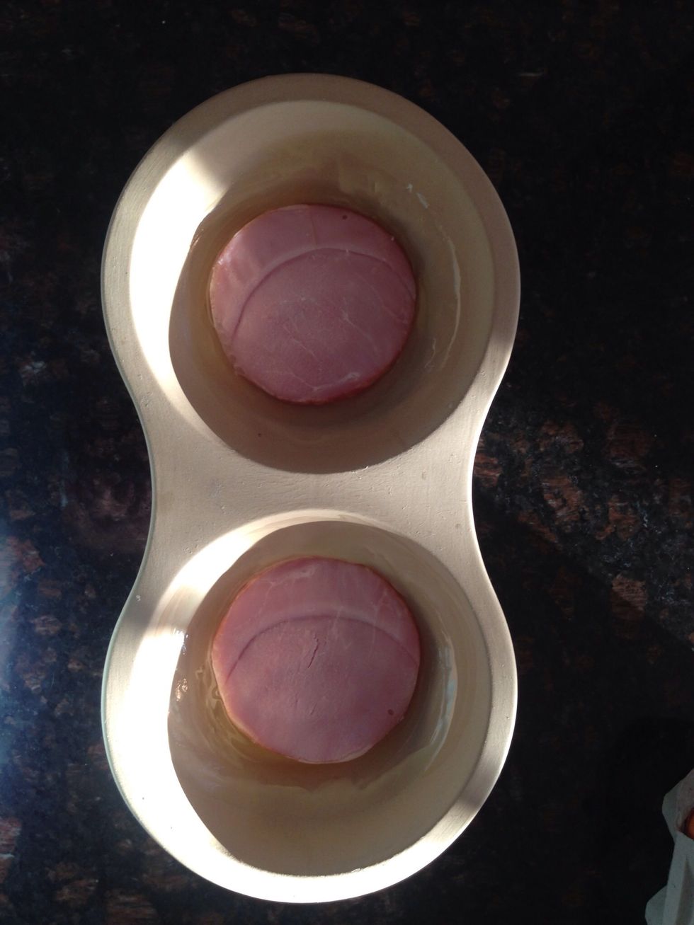 On top of the raw egg, add 1 slice Canadian Bacon on each.