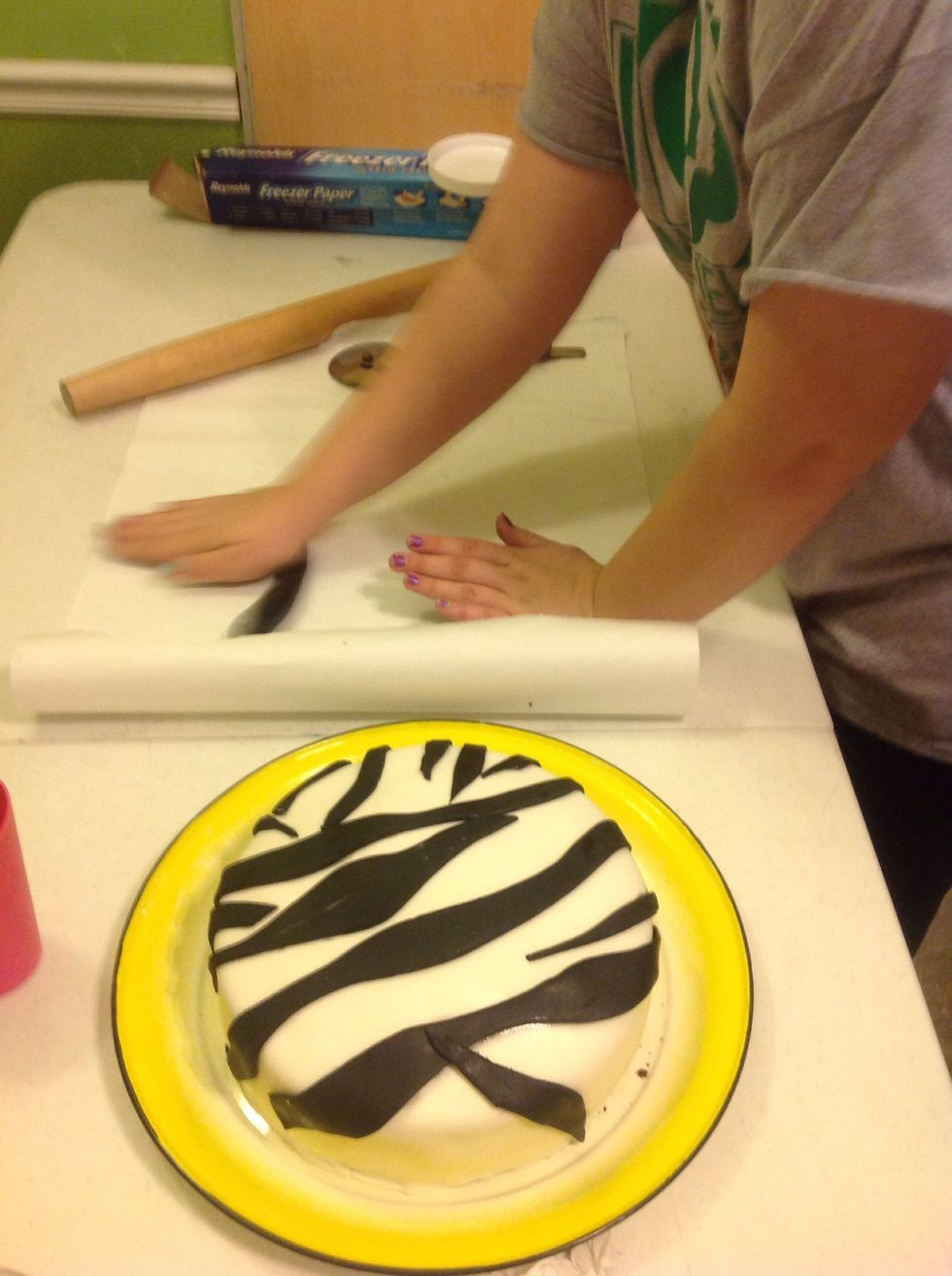 Once all stripes are placed on cake take extra fondant and begin to roll out into a long string.