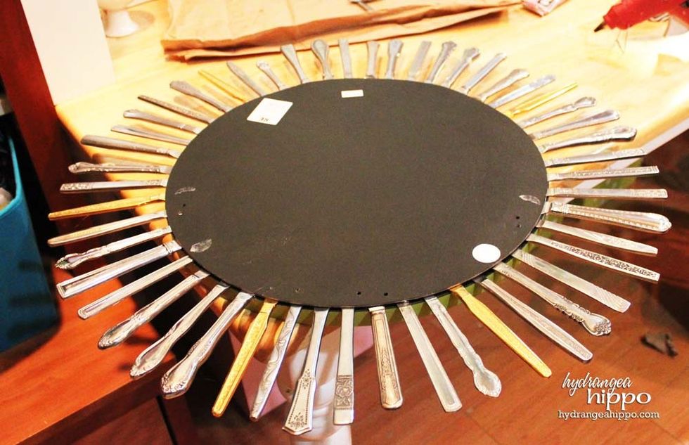 Once all the knives are in place, cut a piece of wood or chipboard to to the size of the mirror to cover them. This \u201csandwich\u201d will help make the mirror sturdier.