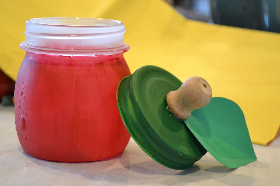 Once both have dried place a glue dot on the bottom of the wooden knob. Cut a leaf shape out of your green construction paper and place leaf on knob. Place another glue dot on leaf and press to jar.