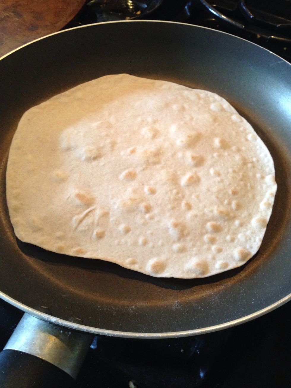 Once bubbles form, slide the tortilla towards the side of the pan, like you were going to slide it out. It should be cool enough to the touch to pick up and flip over.