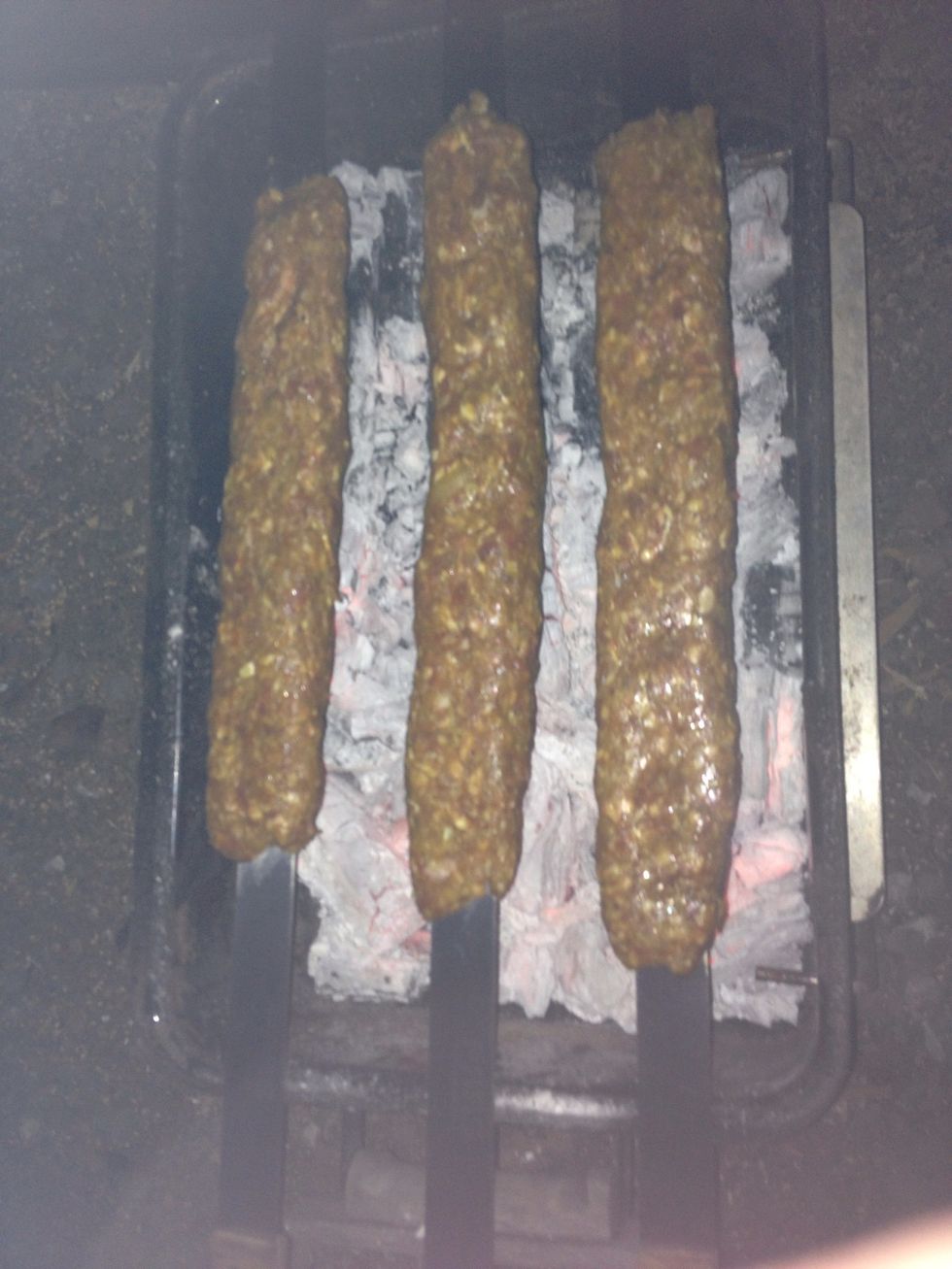 Once charcoal is greyed over put on meat. Squeeze the ends one last time to ensure the kababs don't fall apart.  If it starts to break repair it before the whole kabab dominoes and all meat falls off.