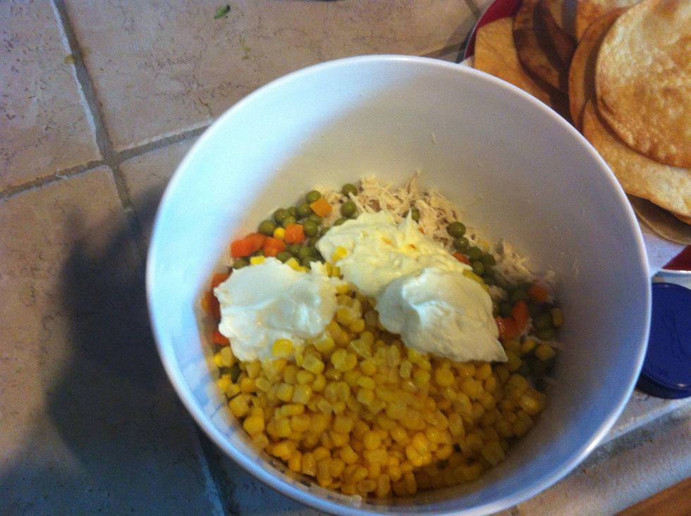 Once chicken is fully cooked, let it cool and shred it. Add about 4 spoonfuls of your mayonnaise. Add the entire can of the peas carrots and corn. Make sure you empty the liquid out of the cans first