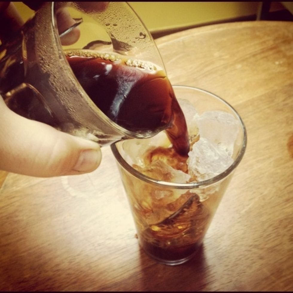 Once coffee finishes dripping, pour into your glass of ice quickly and in a circular pattern very close to the ice.