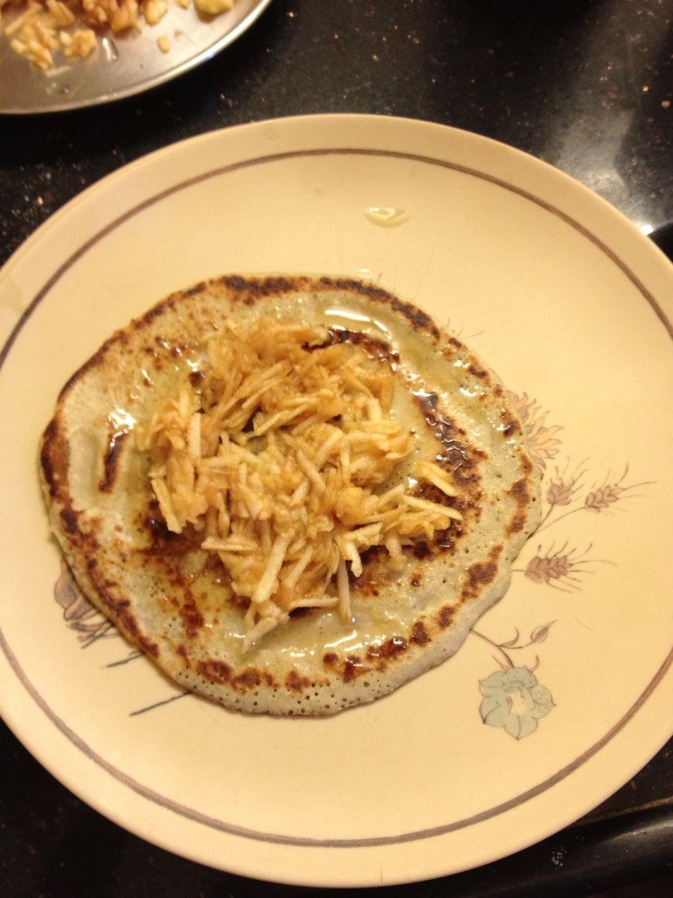 Once cooked, plate it and apply honey on one side and then place the shredded apples and roll the pancake.