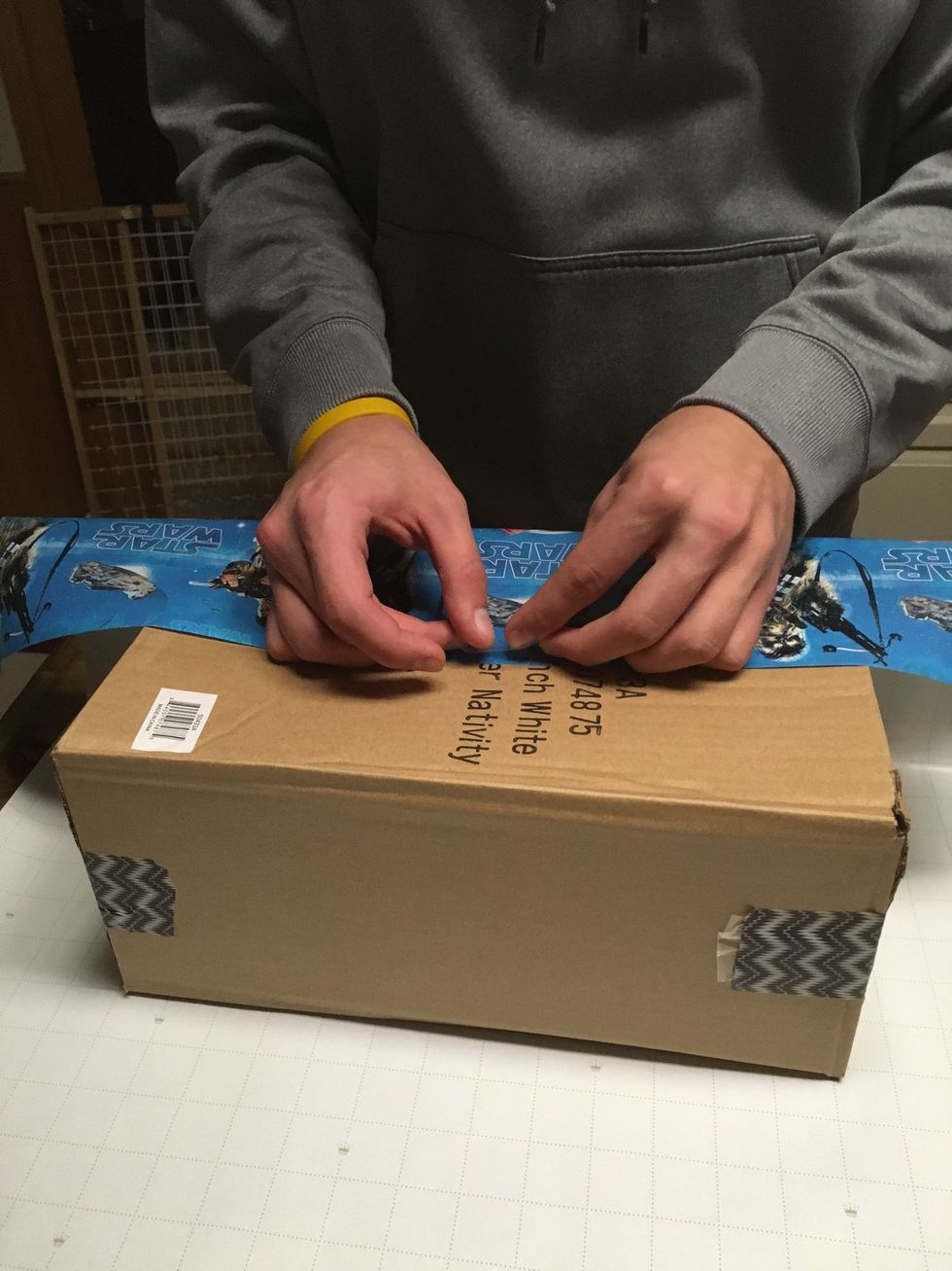 Once cut, fold the side closest to you up. Tape the wrapping paper halfway down the box.