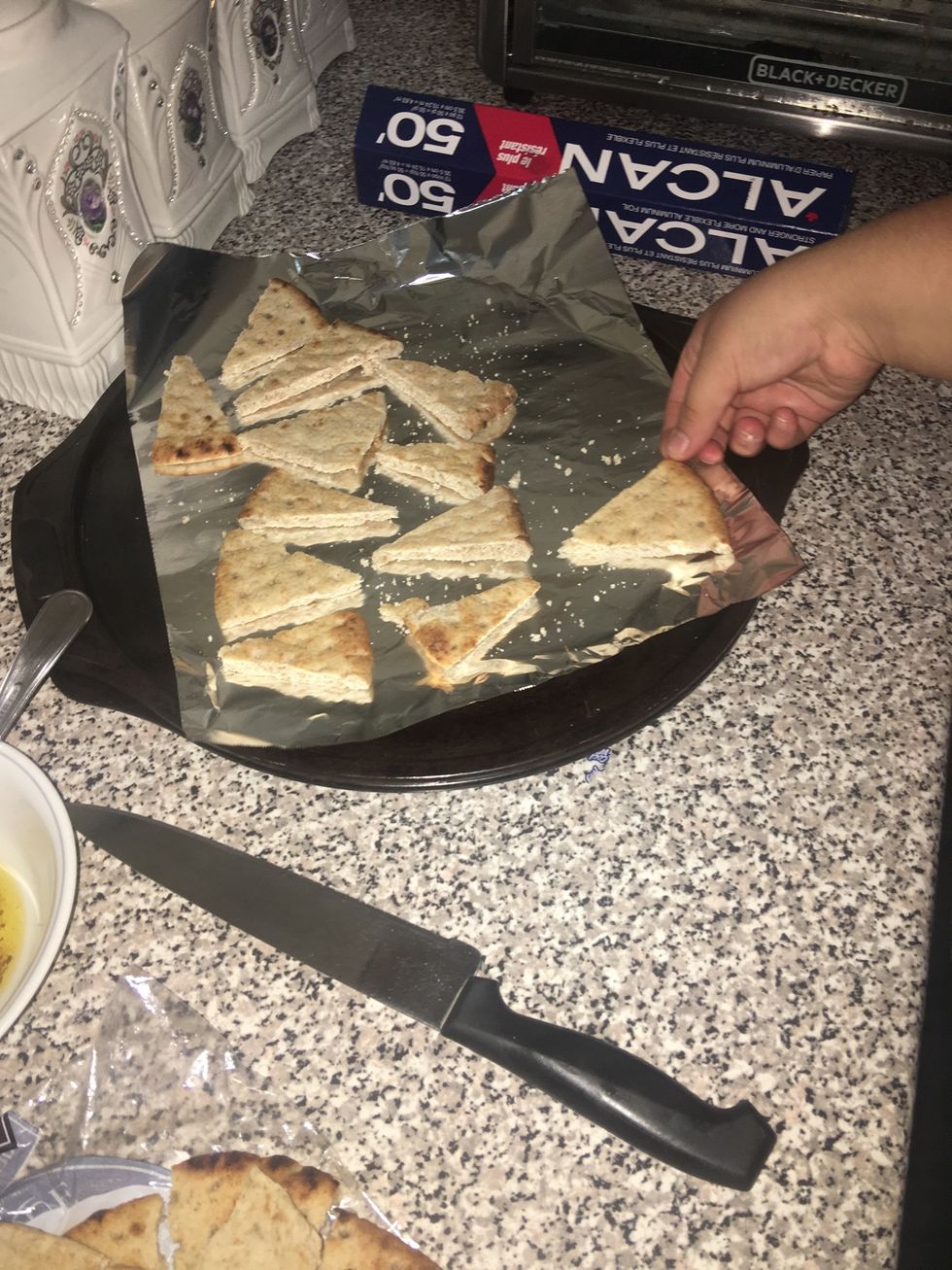 Once done cutting, line a tray with tinfoil or wax paper whichever one you prefer, and place the pitas on top.
