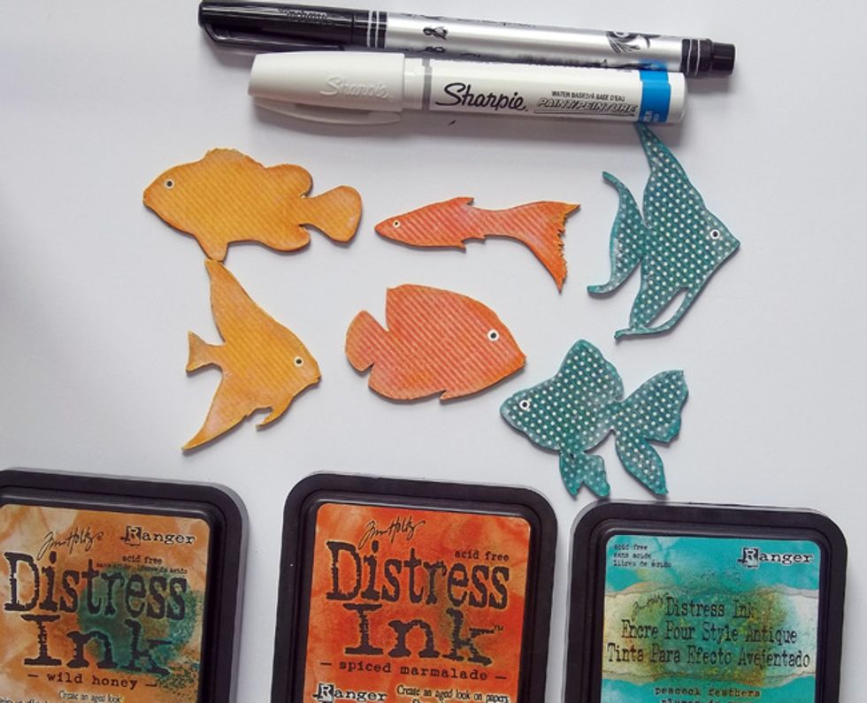 Once dry, fussy-cut out the Tropical Fish. Ink the edges with coordinating Distress Ink and some white gesso. Add a fish eye using a white Sharpie paint pen and a black Sharpie fine tip pen.