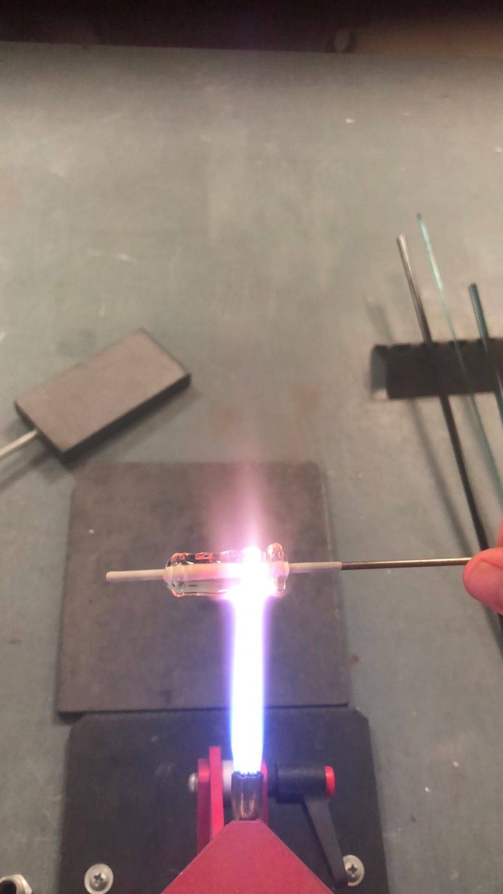 Once enough glass has been applied, heat one end of the bead until the clear begins to soften, but not so hot that it flows freely.