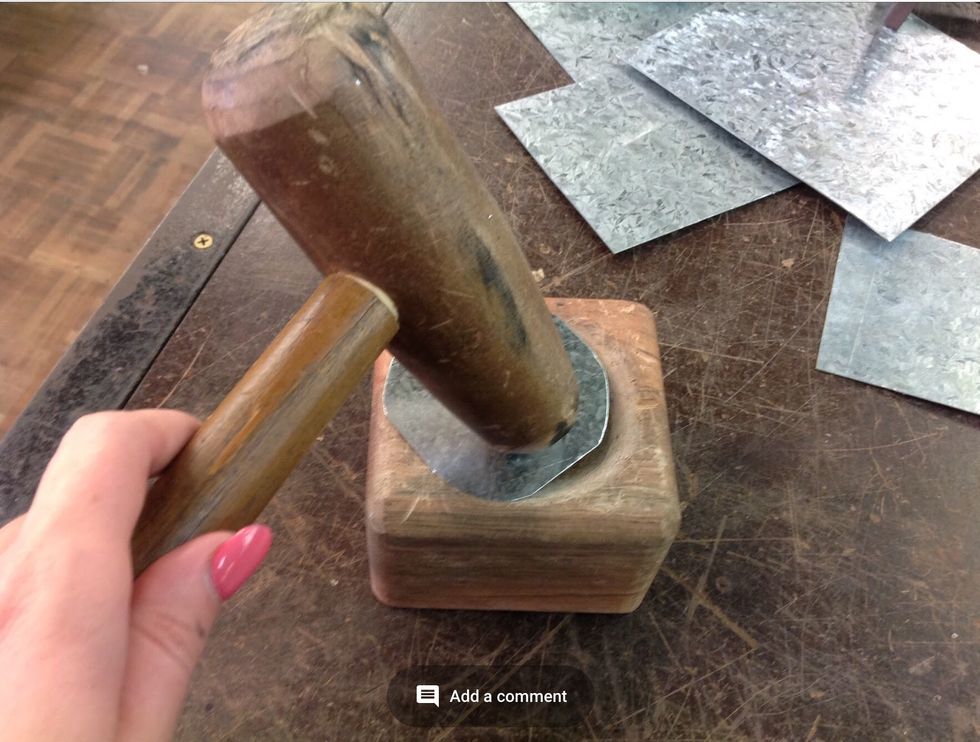 Once filed, place the circle in the wooden mould. Using the tin mans mallet begin to hammer the outsides of the circle to make the circle into a wax catcher