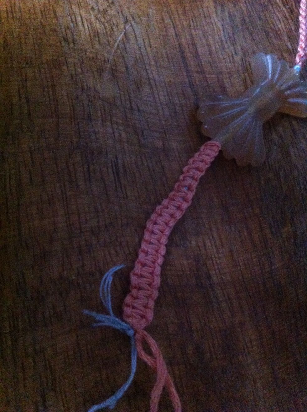 Once finished with the other side of the charm (with the two loose blue cord ends), knot the blue ends several times and trim unwanted ends. Don't cut the pink cords, you need them for the next step.