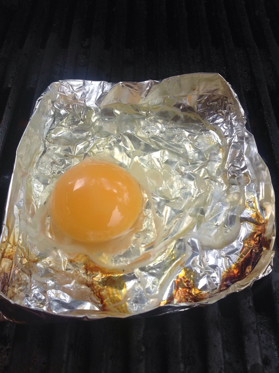 Once heated add the egg you would like to fry to your foil box