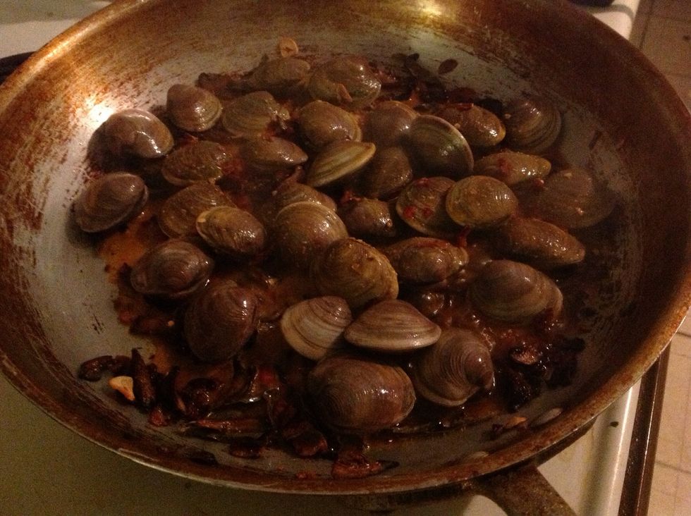 Once mushrooms and shallots are browning, add clams and steaming sauce. Toss to coat and cover to cook until clam shells are open.