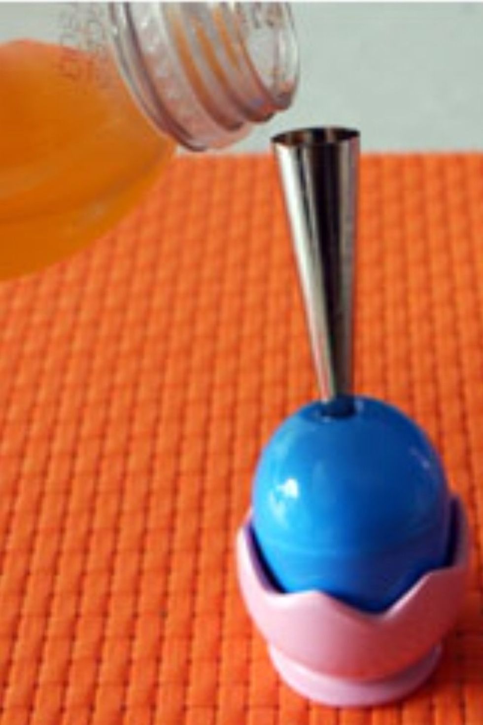 Once piping tip or funnel is in place, pour whatever juice or liquid you'd like into the egg. I recommend pouring over a sink just in case you spill!