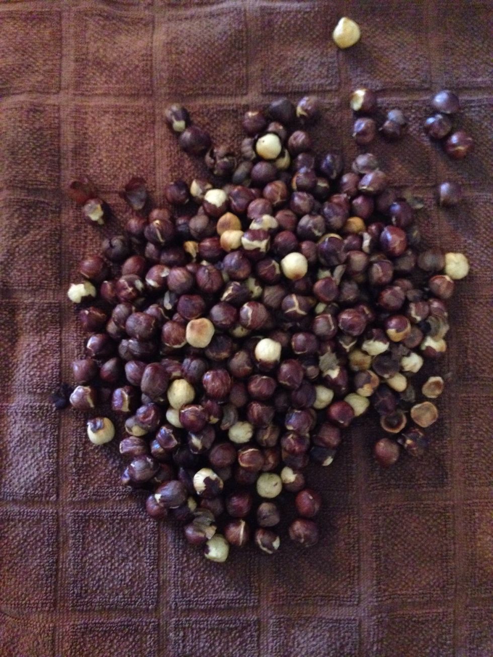 Once roasted, allow nuts to cool for about 5 minutes and then transfer to a clean dish towel. Gather the corners of the towel and roll the bunch on the countertop to rub off the skin.