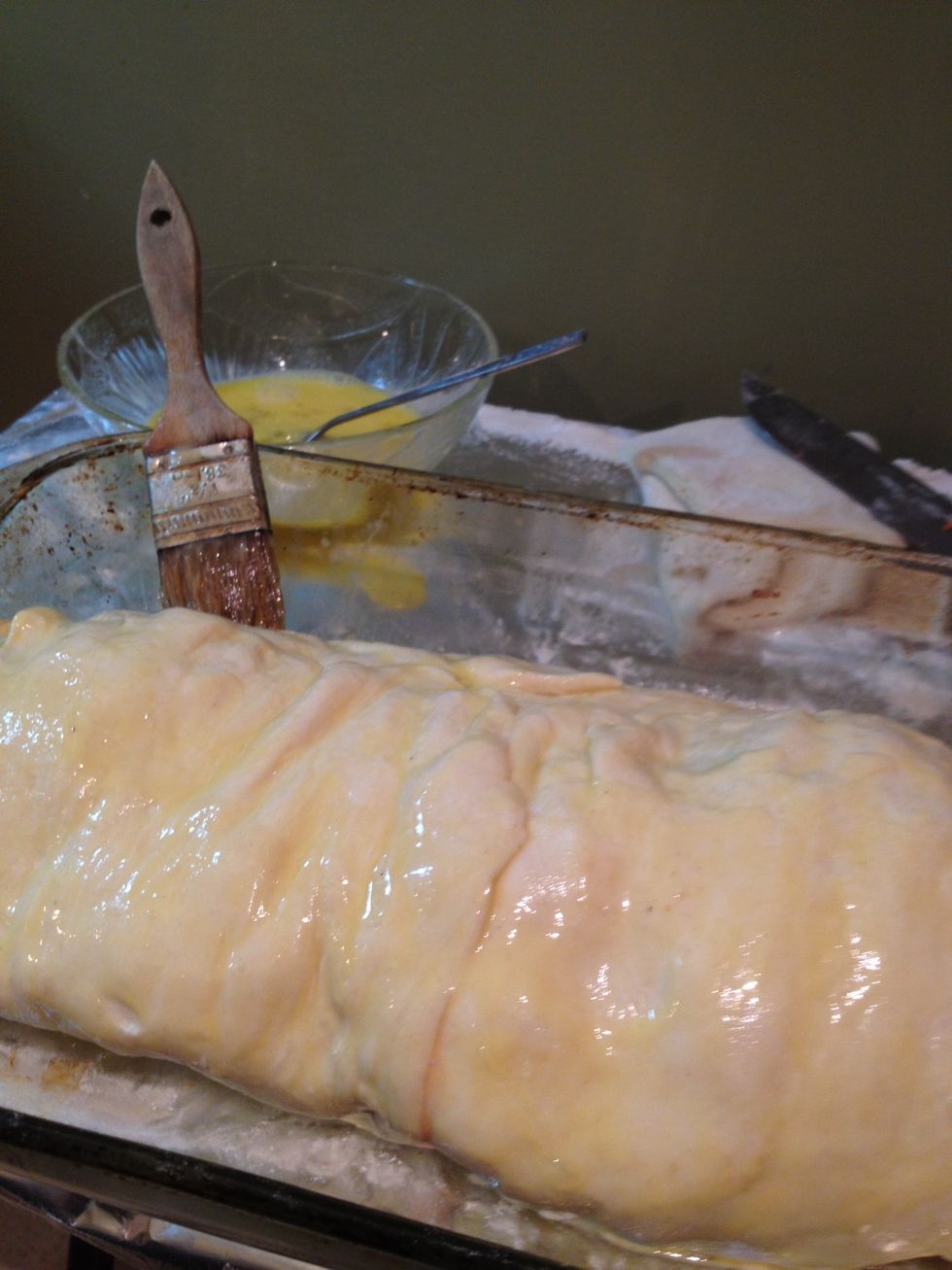 Once rolled up tight, beat the egg yolk and slather all over the puffed pastry.