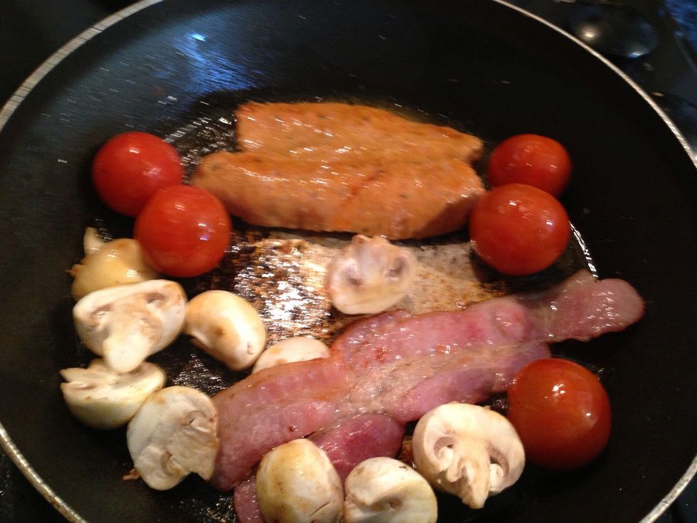 Once the bacon and sausage are browned add the tomatoes and the mushrooms with a knob of butter, make sure to pierce the tomatoes with a knife
