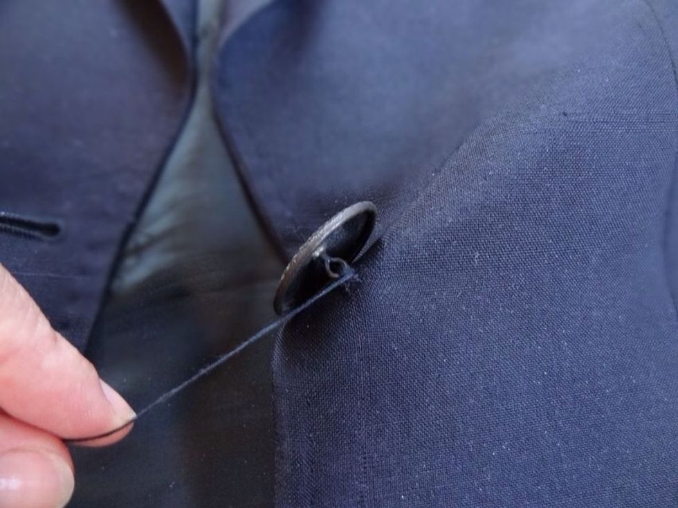 Once the button is fully secure, create a shank by wrapping your thread a few times around the threads which are holding the button to the jacket.