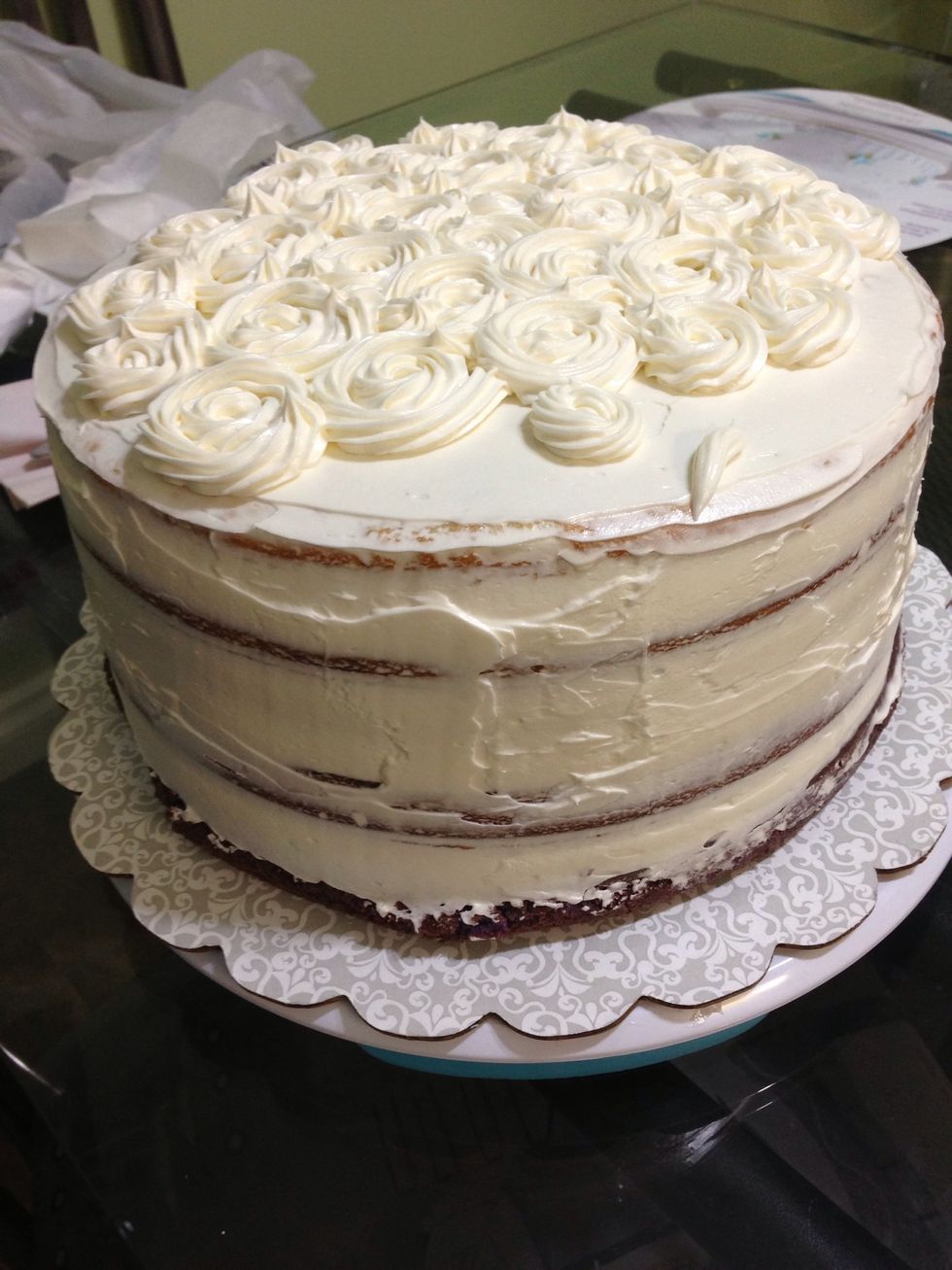 Once the cake is nice and cool, start creating flower designs at the top of the cake. Dye the buttercream darker as you continue further down the cake.