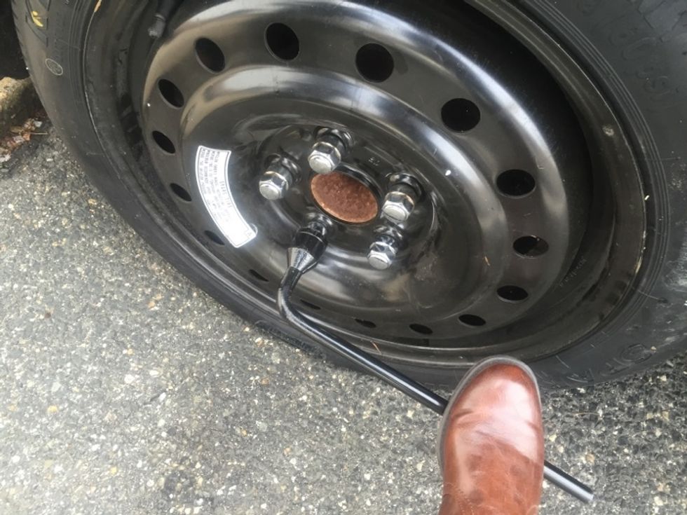 Once the car in on the ground, fully secure the lug nuts using the wrench, exercising caution not to overtighten.