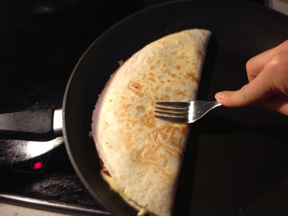 Once the cheese starts to melt, flip. Press hard with fork all around the half side of tortilla. You want to have it as thin as possible, but keeping the cheese inside.
