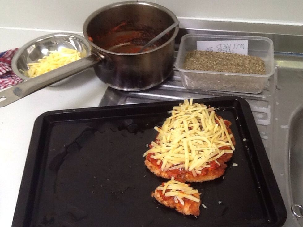 Once the chicken is fried place it on a oiled oven tray. Then spread tomato sauce over the top of the breast followed by grated mozzarella. Then place in a preheated oven at 180 degrees.