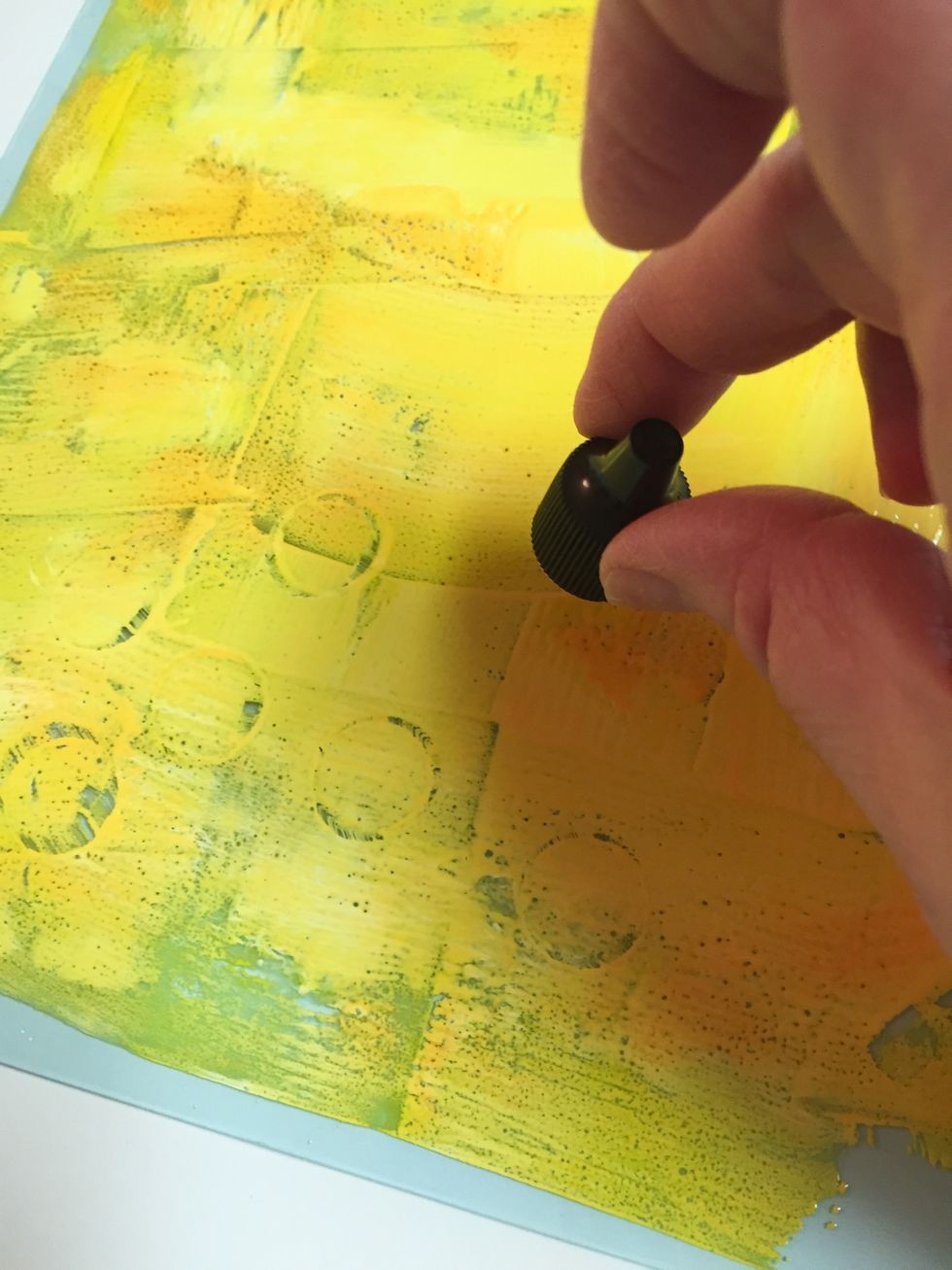 once the colors were spread over the plate using the art wheel, the cap of one of the ink bottles was used to add circles on the plate. a print was made and allowed to dry before proceeding.