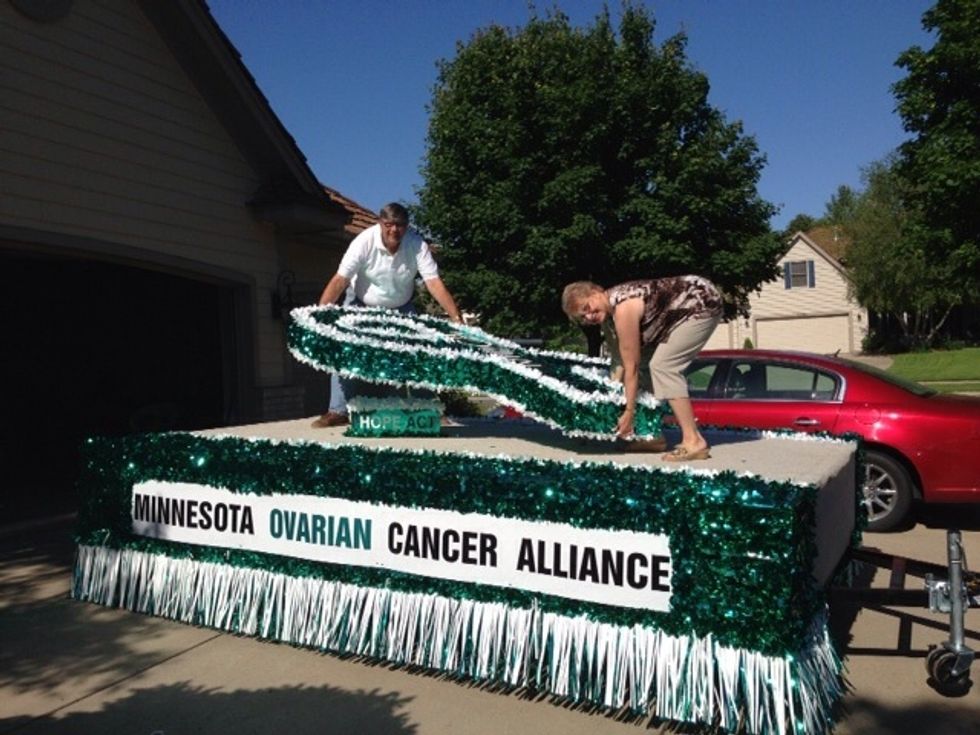 Once the corners are secured, two people should carefully climb on top of the float and pick up the large teal ribbon cut-out.