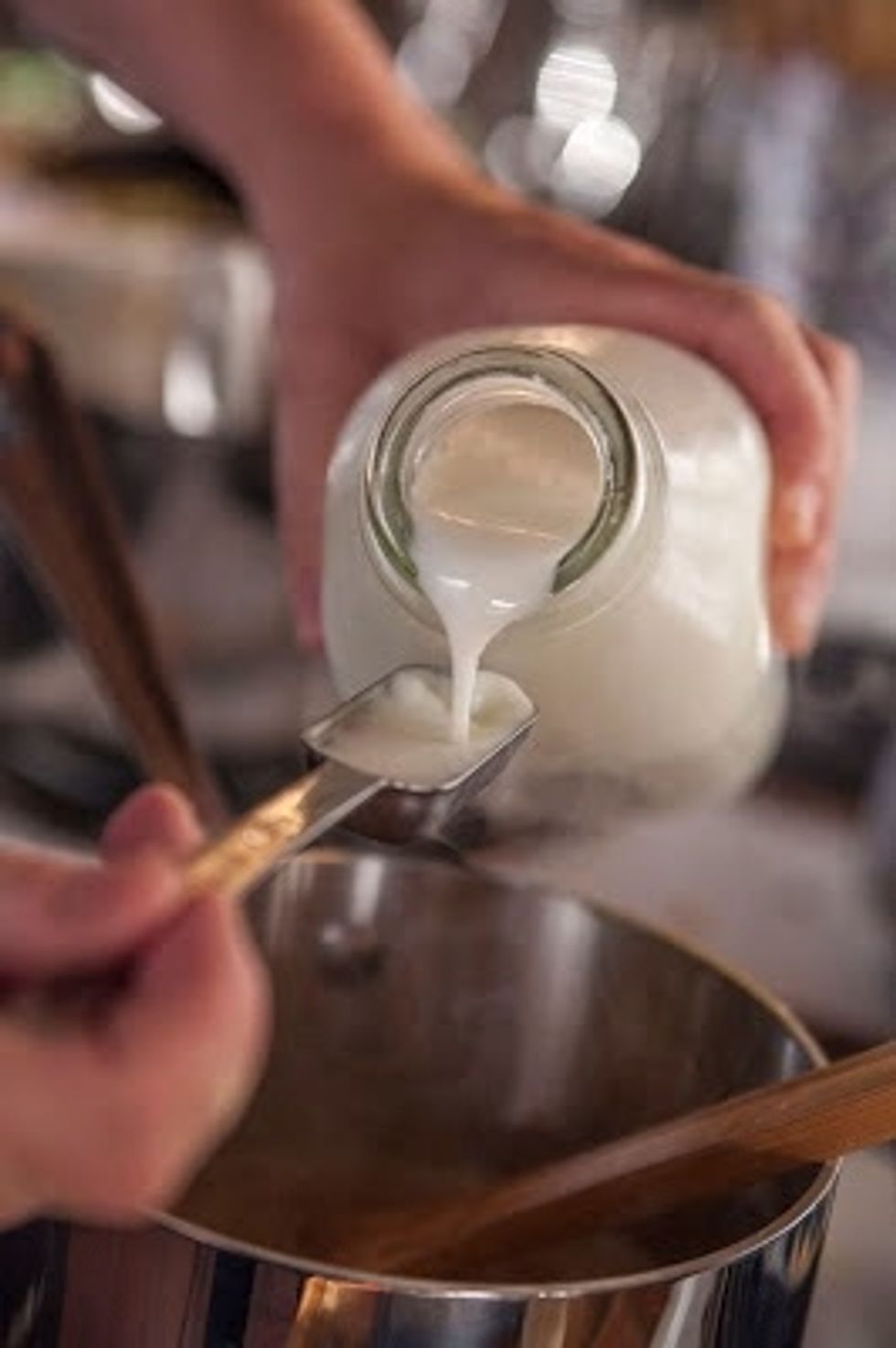 Once the dal and sugar syrup have gotten mashed together pour in the coconut milk. Bring the mixture to a boil, then add in 4 tbs of whole milk, and 2 pinches of ginger.