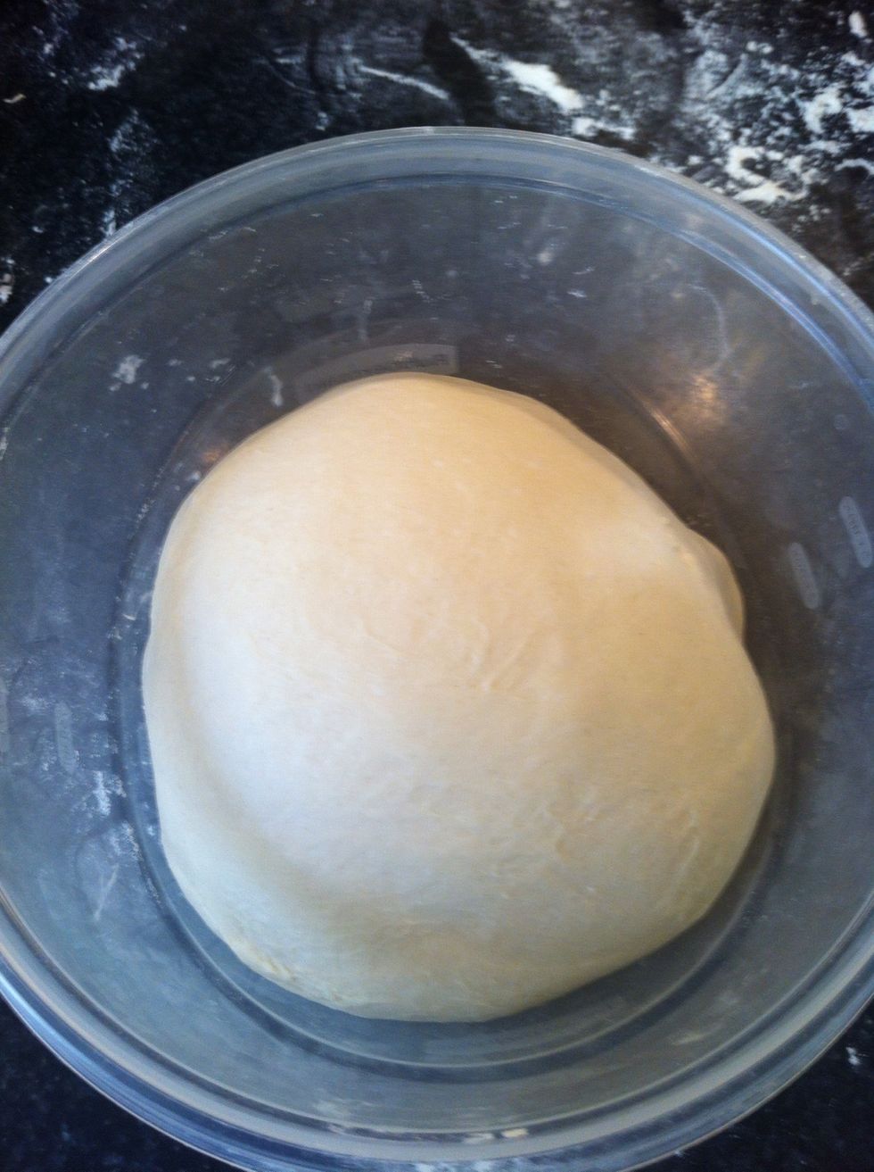 Once the dough is smooth and elastic put it in a large Tupperware container. See how smooth the dough is. And not sticky anymore! It should be slightly tacky but not stick to your hands anymore.