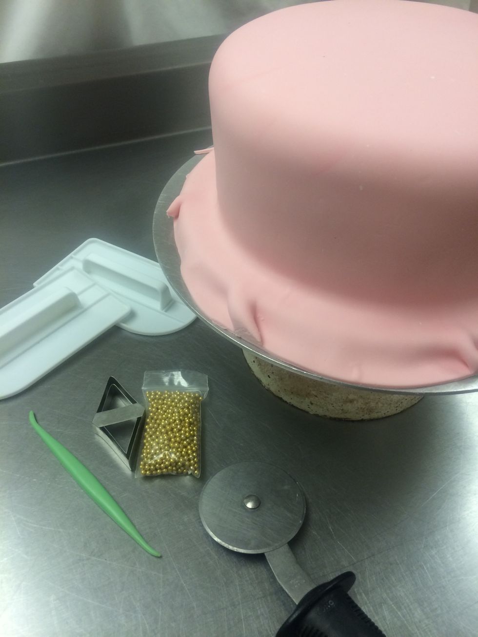 Once the fondant has been applied to the cake we can trim off some extra fondant using a pizza wheel. Use fondant smoothers or paddles to smooth out the fondant and to remove air pockets.