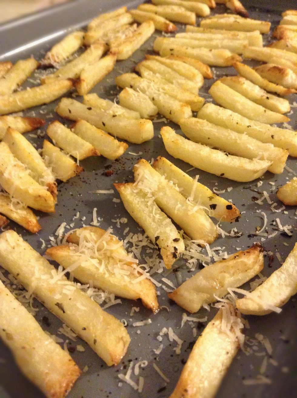 Once the fries are done take them out of the oven and sprinkle on the parmesan cheese. You want the fries to be fresh out of the oven so the cheese will melt a bit.